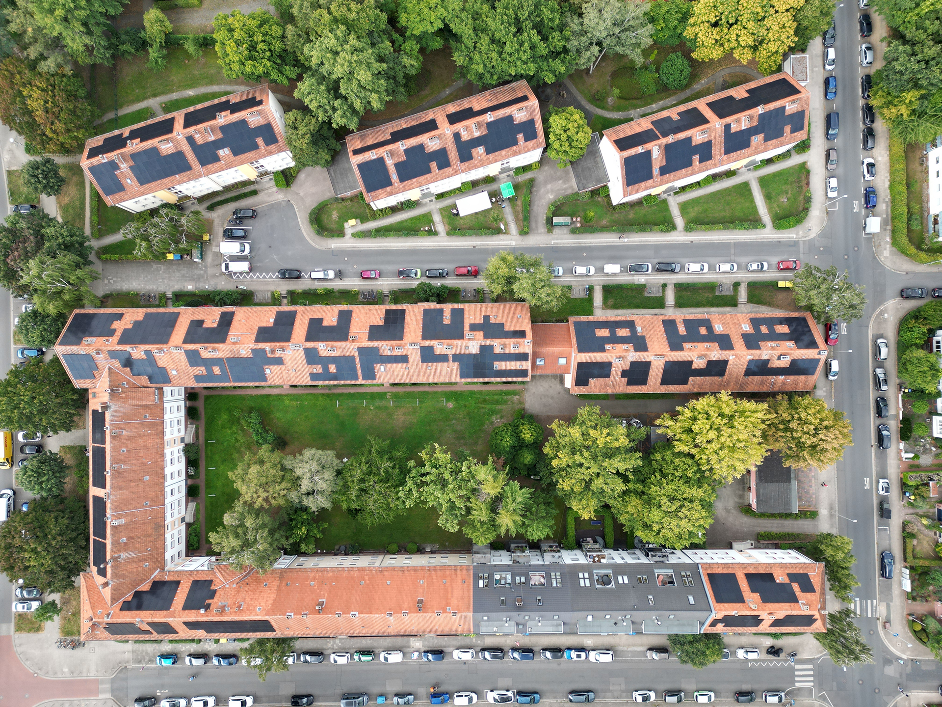 Ansicht von oben auf Mehrfamilienhäuser mit PV-Anlagen.